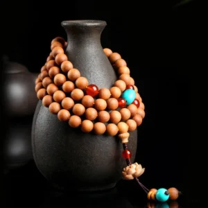 Tibetan prayer mala beads wrapped on ceramic vase with lotus charm accent