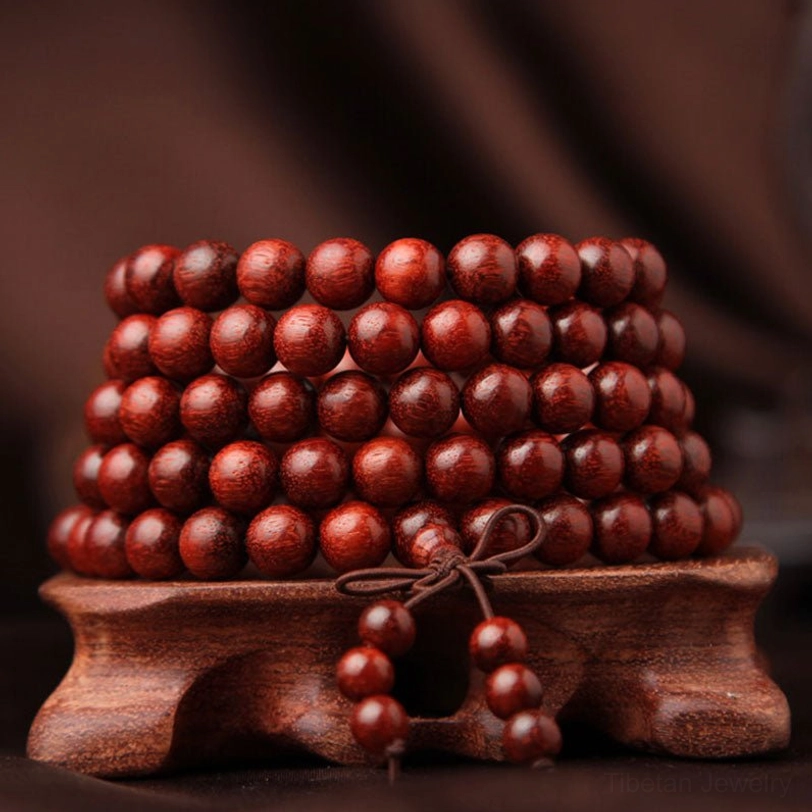 Stacked 108 bead sandalwood malas from top-down perspective on wooden display base, showing dense arrangement of reddish-brown beads