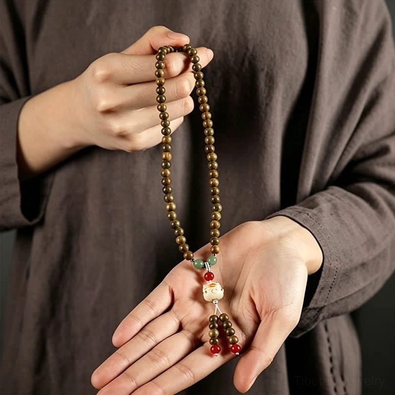 Sandalwood mala bracelet with cat charm tassel pendant on wooden surface showing artisanal craftsmanship