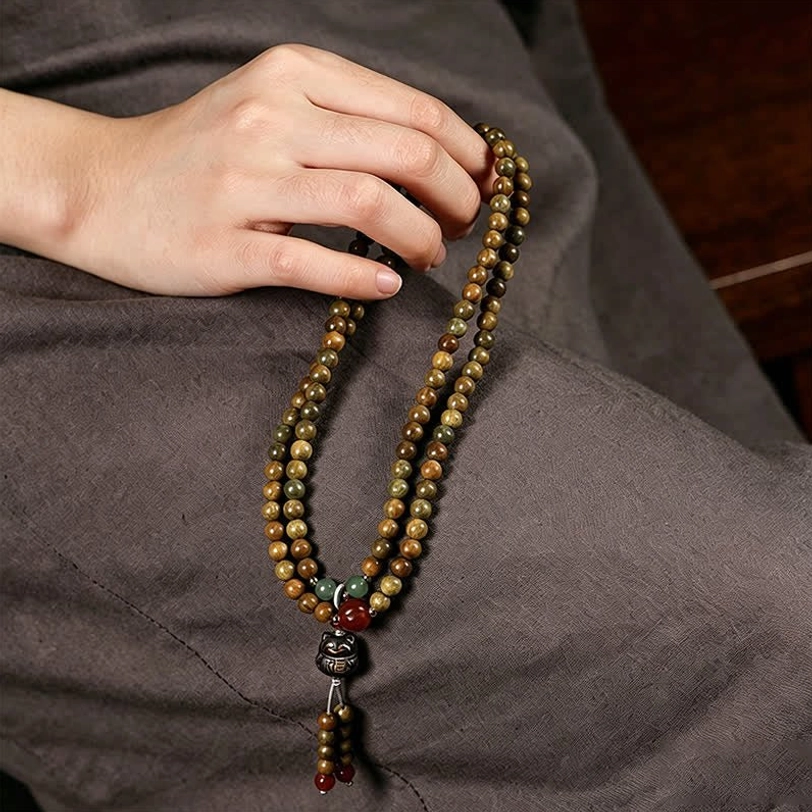 Multi-strand sandalwood mala bracelet with cat tassel pendant styled on neutral background
