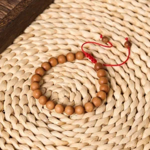 Handcrafted sandalwood prayer beads wrist mala on woven straw mat background, meditation bracelet close-up