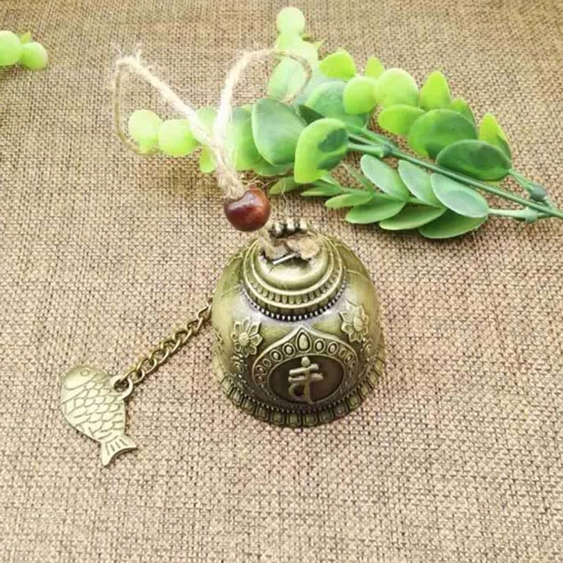 Sanskrit carved bronze Tibetan wind chime with embossed sacred symbols and hemp rope hanger on natural jute cloth