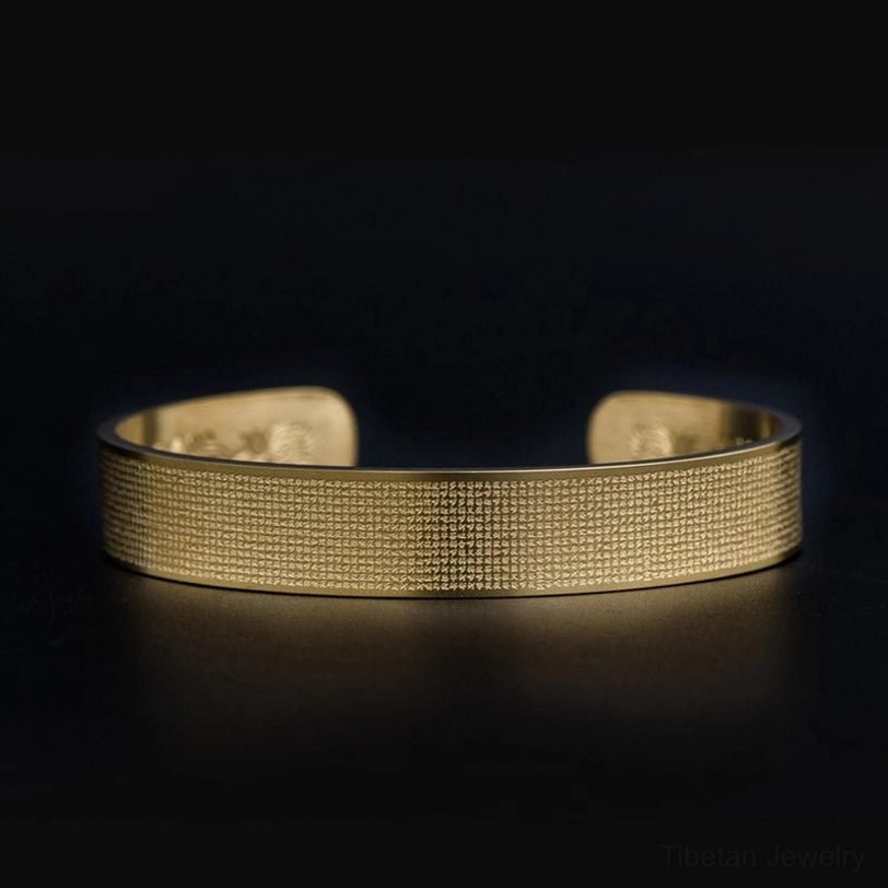 Shurangama mantra engraved titanium steel cuff bracelet - front overhead view showing sacred Sanskrit text carving on gold-toned open cuff