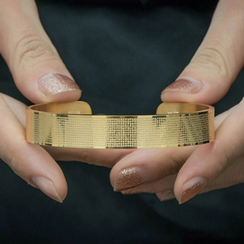 Shurangama mantra engraved titanium steel bracelet held in hands displaying full width of textured band with complete sacred mantra inscription