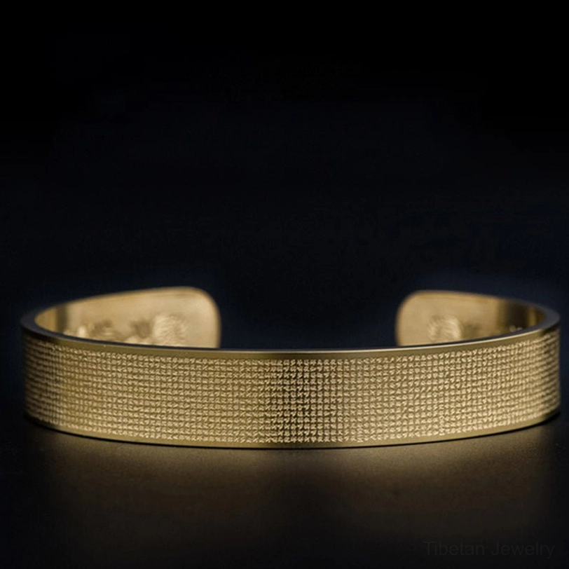 Shurangama mantra titanium steel cuff bracelet held in hands showing textured engraved exterior surface and craftsmanship details