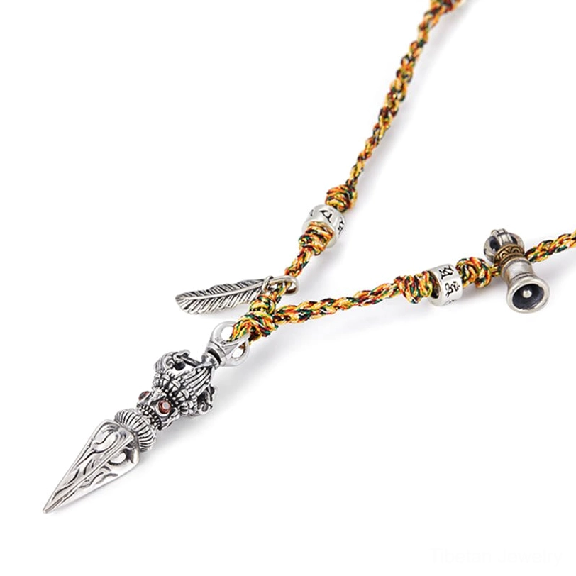 Low-angle flat lay of 925 sterling silver Dorje pendant necklace with engraved beads, feather accent, and woven brown-gold cord