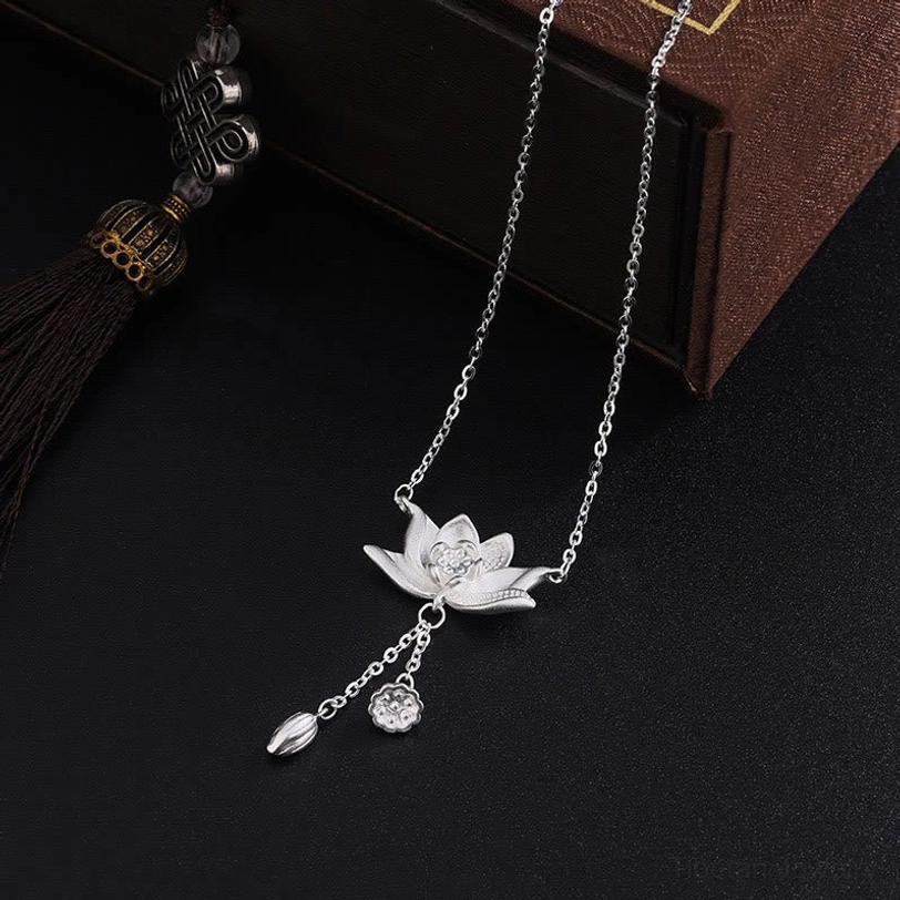 Handcrafted silver lotus pod necklace with dual drop pendants and adjustable cable chain on vintage wooden display