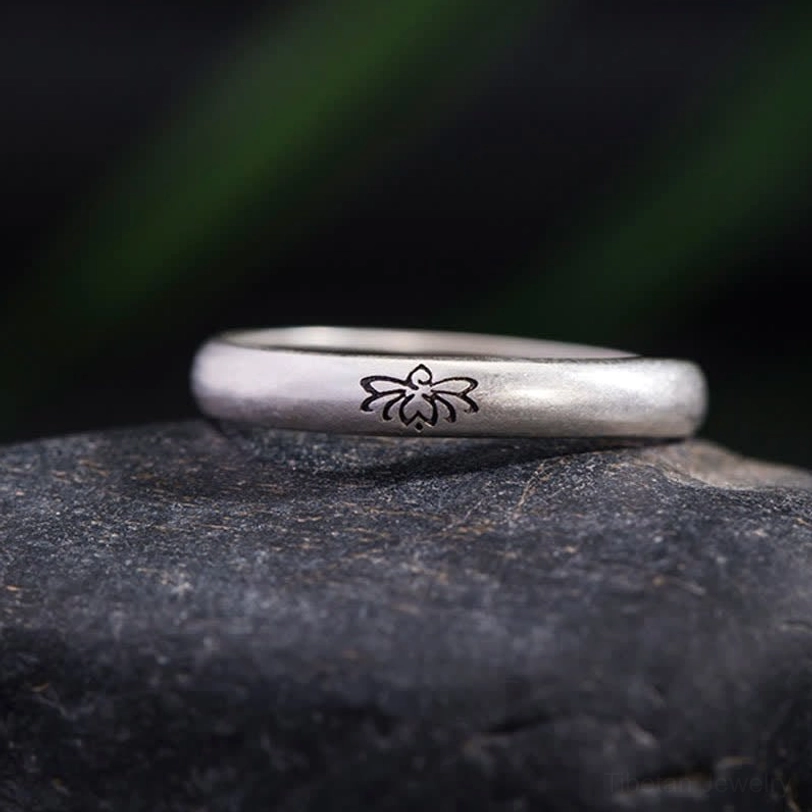 Hand-engraved lotus motif 925 sterling silver open ring flat front view on dark stone