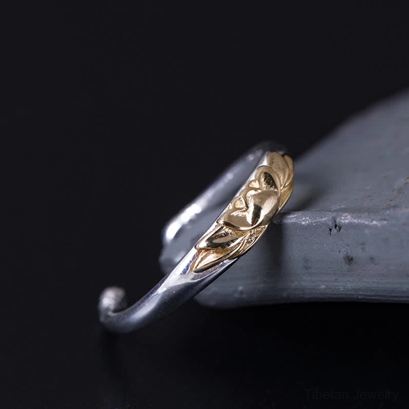 Sterling silver lotus cuff ring low angle view displaying curved band and embossed gold lotus design