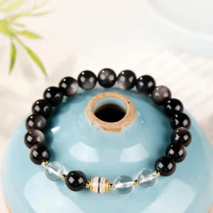Silver Sheen Obsidian Nine-Eye Dzi Bead Protection Bracelet top-down view with clear quartz spacers and hand-painted Dzi bead