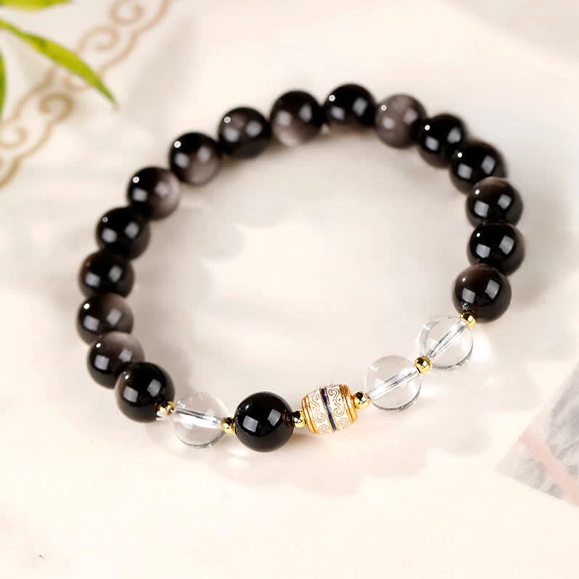 Silver Sheen Obsidian Nine-Eye Dzi Bead Protection Bracelet looped layout with bamboo background
