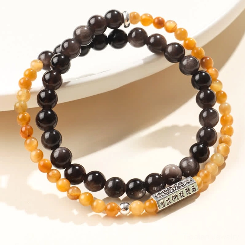 Silver Sheen Obsidian Om Mani Padme Hum double wrap bracelet with warm golden-yellow and dark obsidian beads resting on white ceramic plate