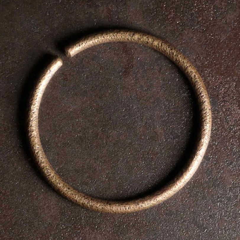 Single open-ended hammered copper cuff bracelet with warm bronze tone, overhead view