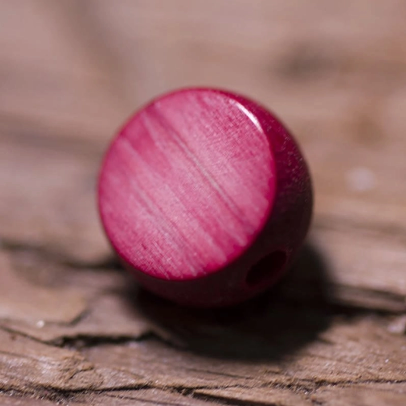 Individual red wooden mala bead macro photography revealing natural wood grain pattern and authentic handcrafted drilling