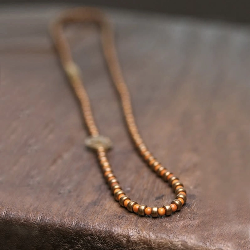 Single-strand handmade olive pit wealth bracelet in flat lay side view featuring small metal spacer knot detail