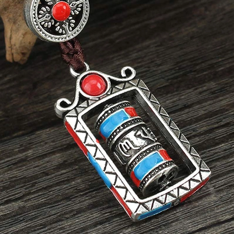Om Mani Padme Hum prayer wheel keychain close-up, rotatable mechanism detail, silver alloy frame with traditional Tibetan symbols