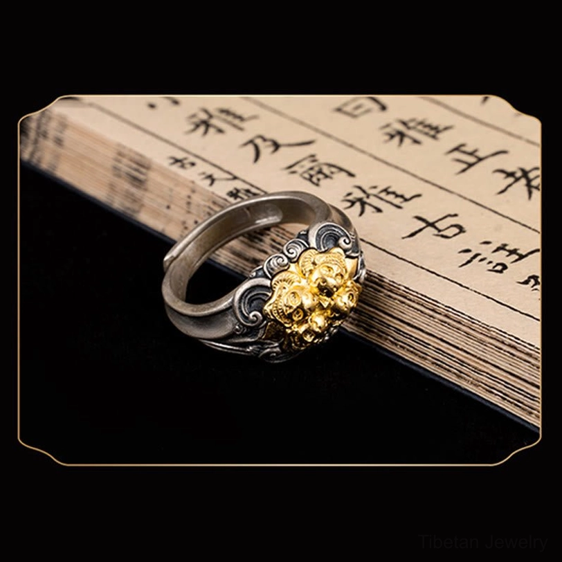 Dual-tone silver Tibetan skull ring displayed on antique Chinese calligraphy book page showing elegant side oblique angle