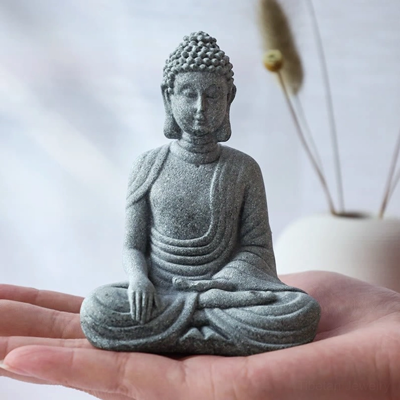 Small seated Buddha figurine handcrafted grey sandstone meditation pose close-up