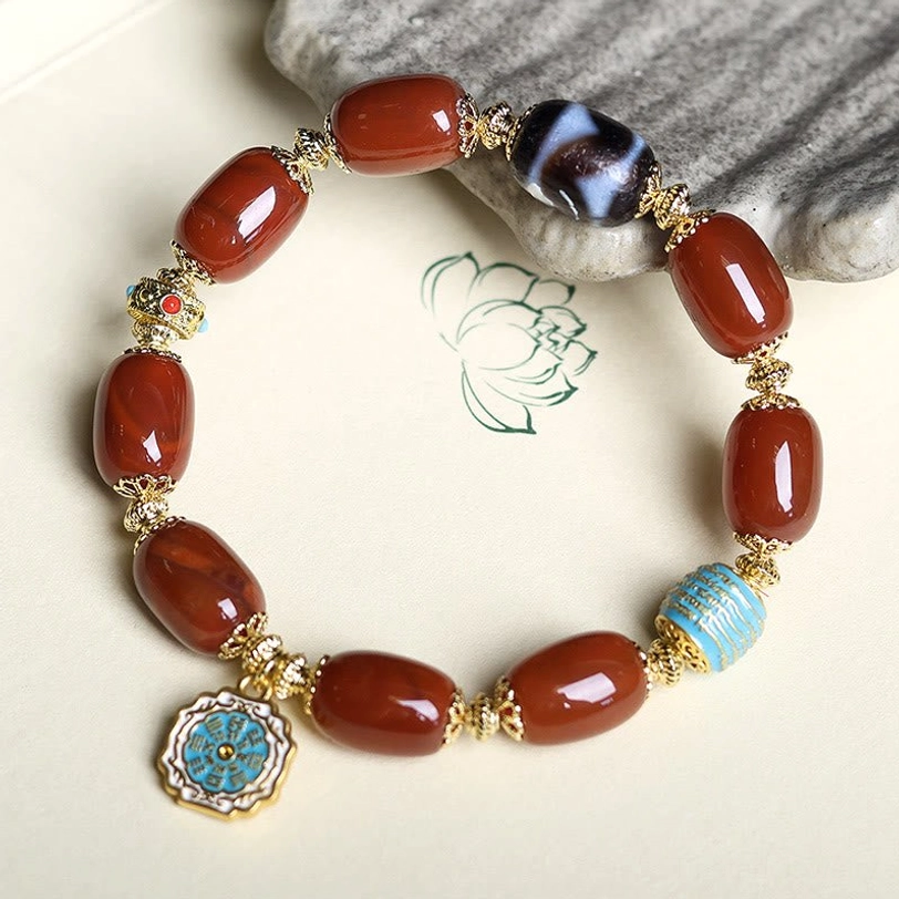 South Red Agate Bagua Dzi Bead Bracelet on light lotus-patterned background, showcasing red agate beads with blue enamel Bagua charm