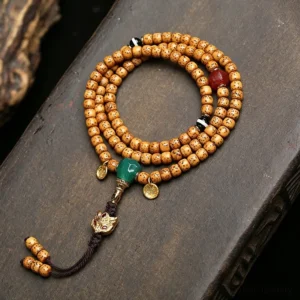 Star Moon Bodhi 108 prayer mala beads flat lay overhead view on dark wood showing authentic tan spotted beads with green accents and metal guru charm