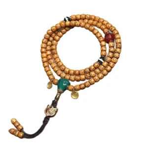 Tibetan Star Moon Bodhi mala beads flat lay with green spacer and ornate metal charm on wooden surface showcasing traditional Buddhist prayer necklace