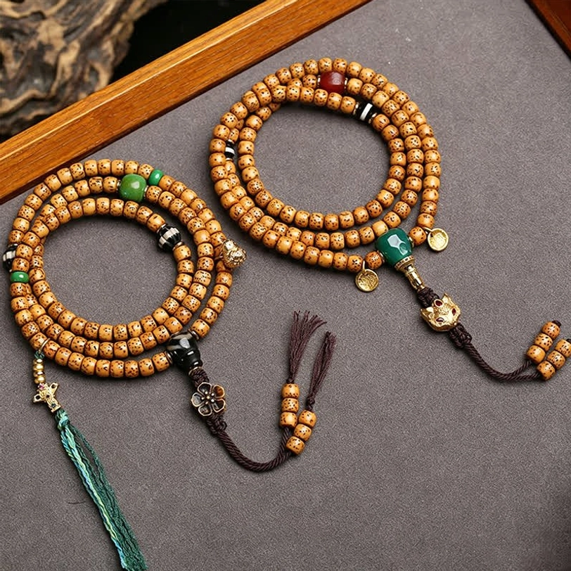 Two handcrafted Star Moon Bodhi 108 prayer malas on wooden tray showing tan spotted beads with green tassels metal accessories and braided cords