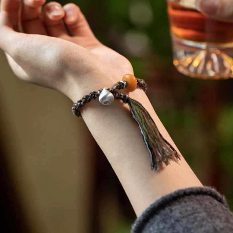 Styled photo of amber steelyard bracelet worn on wrist with casual background and glass accessory showing amber bead and silver charm detail
