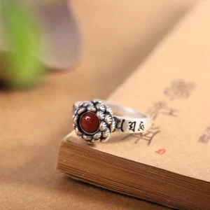 Handcrafted sterling silver lotus red agate confidence ring, top-side angle on vintage book