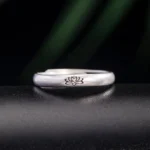 925 sterling silver lotus flower ring with adjustable open band, front view on dark leather background