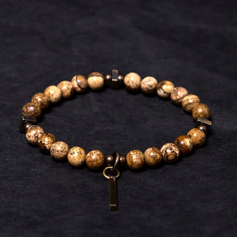 Spotted natural stone beaded bracelet three-quarter angle, aged copper hardware and dangling bar tag