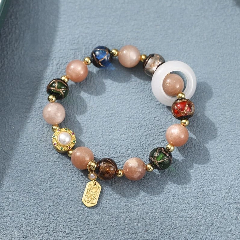 Tibetan bracelet featuring sun stone, enamel mantra beads, and gold metal pendant with jade ring accent