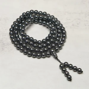 108 terahertz mala beads coiled flat lay with metallic dark beads and tassel pendant on grey tabletop