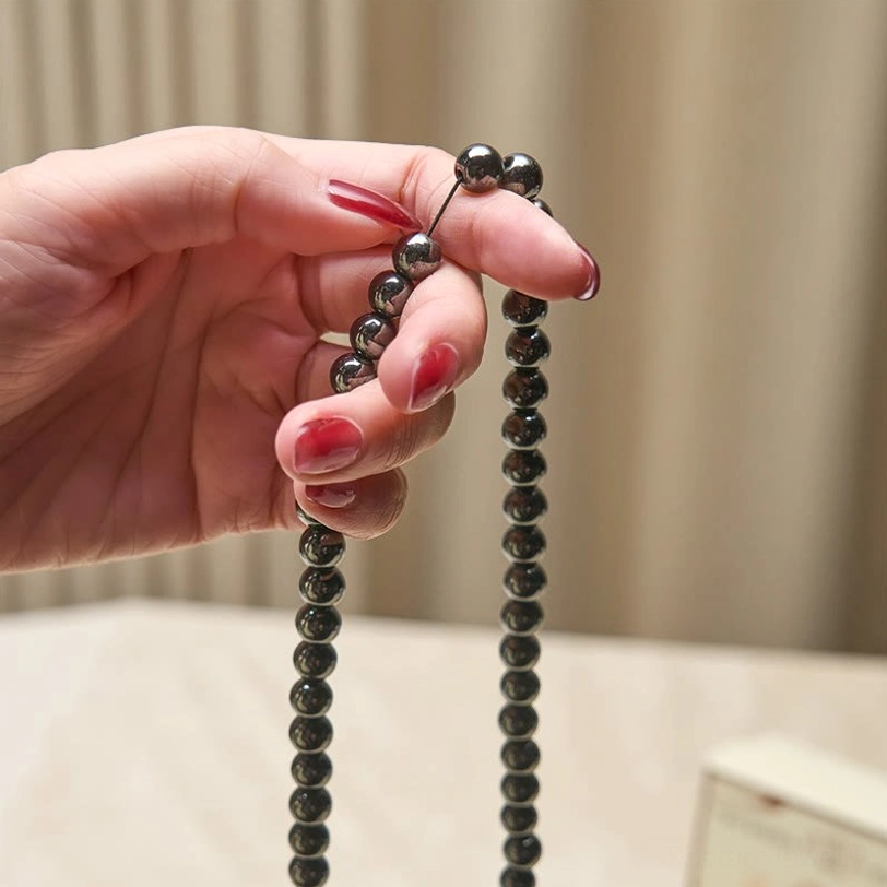 Terahertz 108-bead mala held between fingers showing bead detail and hanging chain