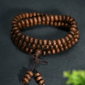 Coiled natural wood prayer mala beads in flat lay - textured wooden beads with simple knotted tassel pendant - meditation necklace