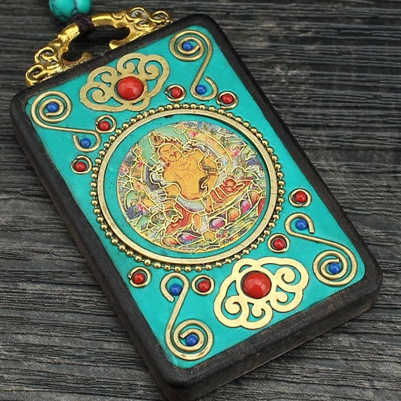 Close-up detail of Five Gods of Wealth thangka pendant showing intricate turquoise Buddha art, gold filigree work, and red and blue gemstone inlays with ebony frame