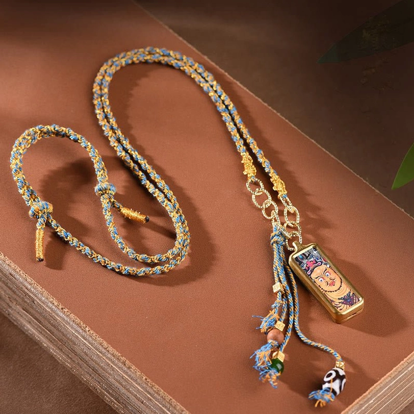 Tibetan wealth god thangka pendant necklace flat lay overhead view with tassel beads on book backdrop