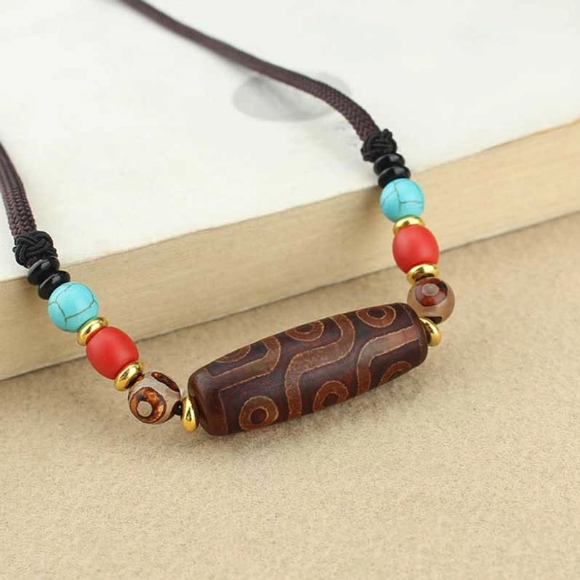 Three-eye dzi bead pendant necklace showing authentic natural agate material with three circular eye patterns and braided cord