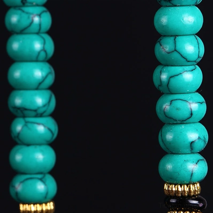 Three-eye dzi bead with gold metal spacers and natural turquoise vein patterns macro detail