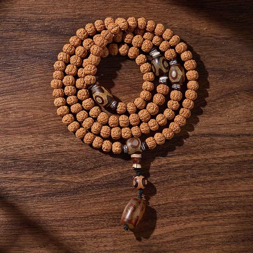 Detailed view of three-eye dzi beads integrated within 108-bead bodhi seed mala, showing protective amulet craftsmanship