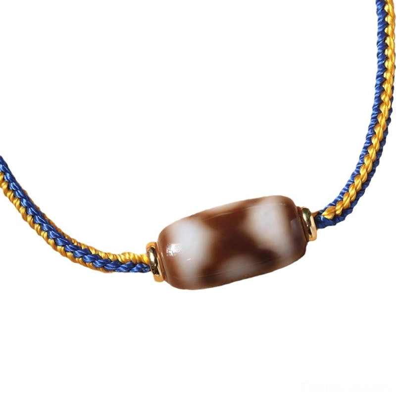 Three-eye Dzi bead bracelet full view, adjustable design with sliding knot on wooden background