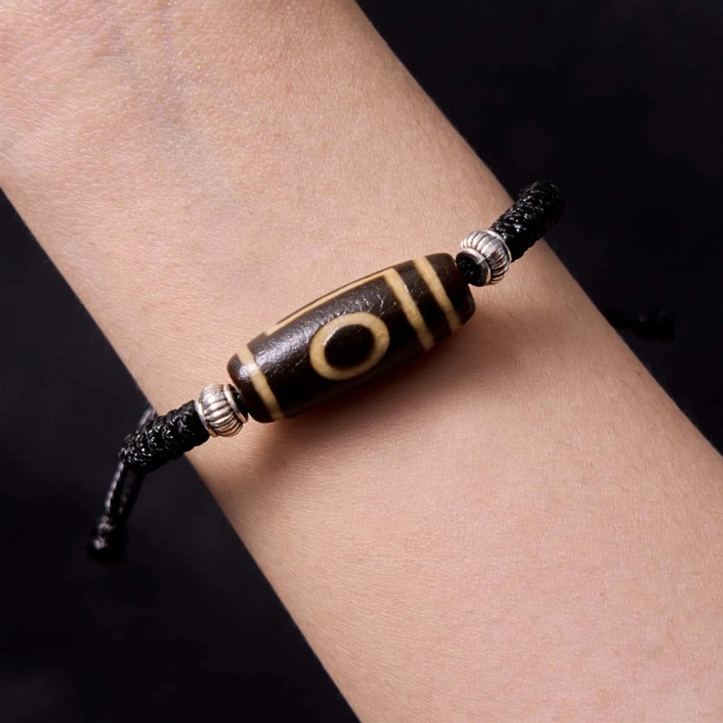 Tibetan three-eye dzi bead worn on wrist demonstrating fit and authentic hand-painted bead craftsmanship