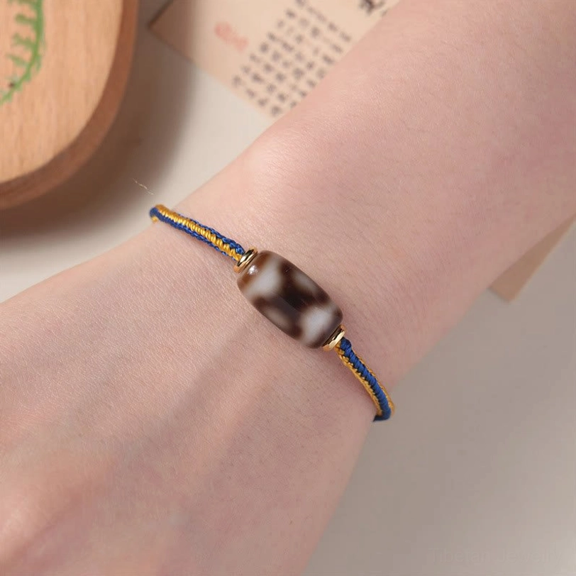 Three-eye Dzi bead bracelet worn on wrist, showing real-life fit and how blue-gold cord drapes on skin