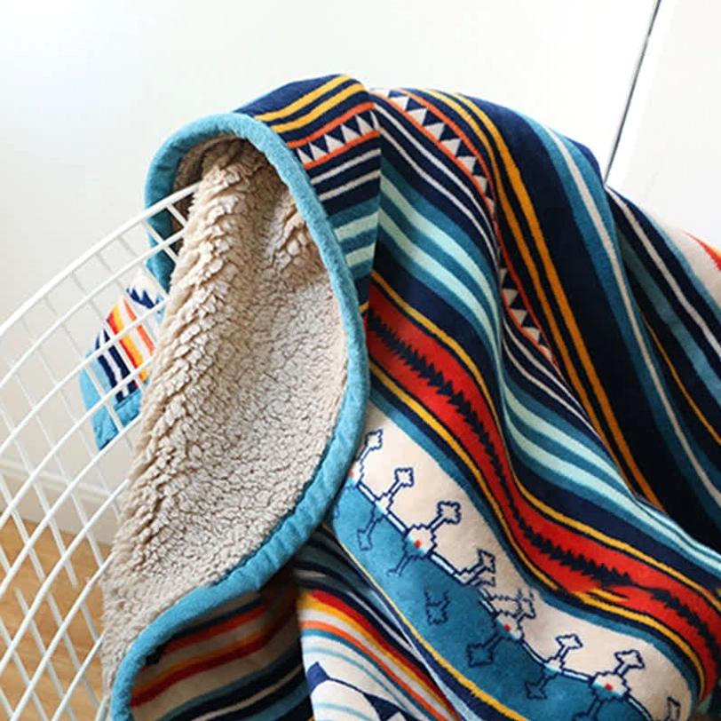 Close-up detail of throw blanket showing sherpa lining, flannel front with detailed aztec motifs and blue trim, texture-focused product shot
