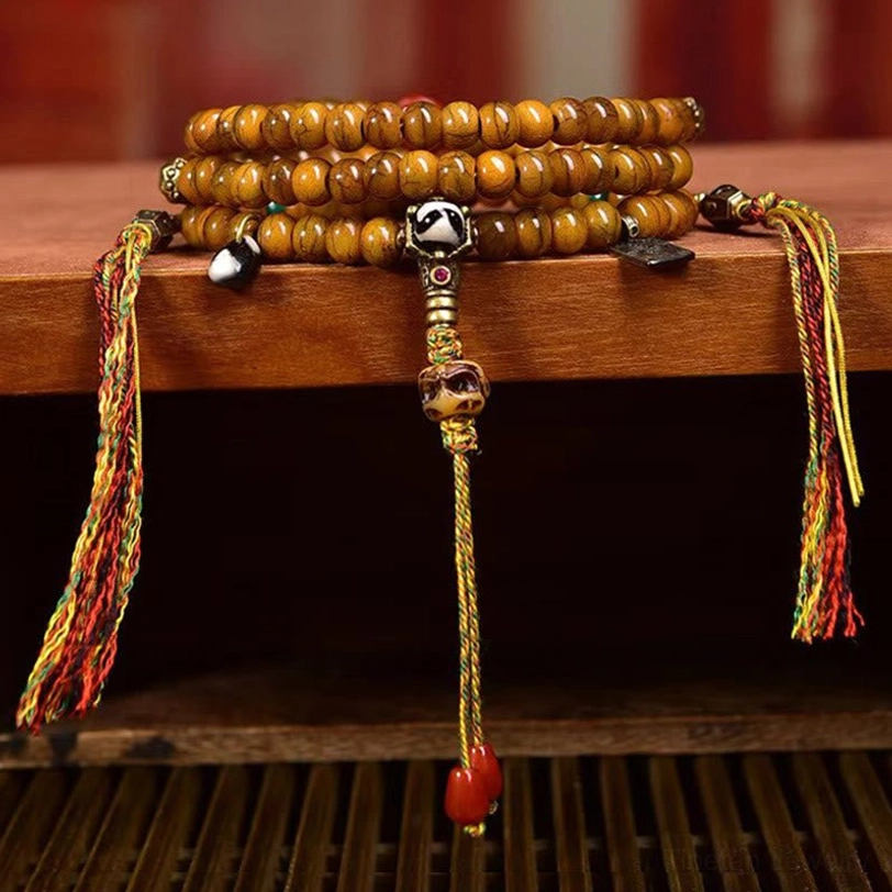 Stacked Tibetan mala bracelets with uniform bone beads, silver guru bead, and woven side tassels - front display