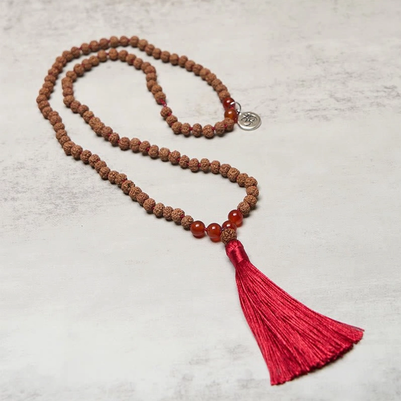Long 108 bodhi seed mala necklace with red agate beads and Om charm overhead view