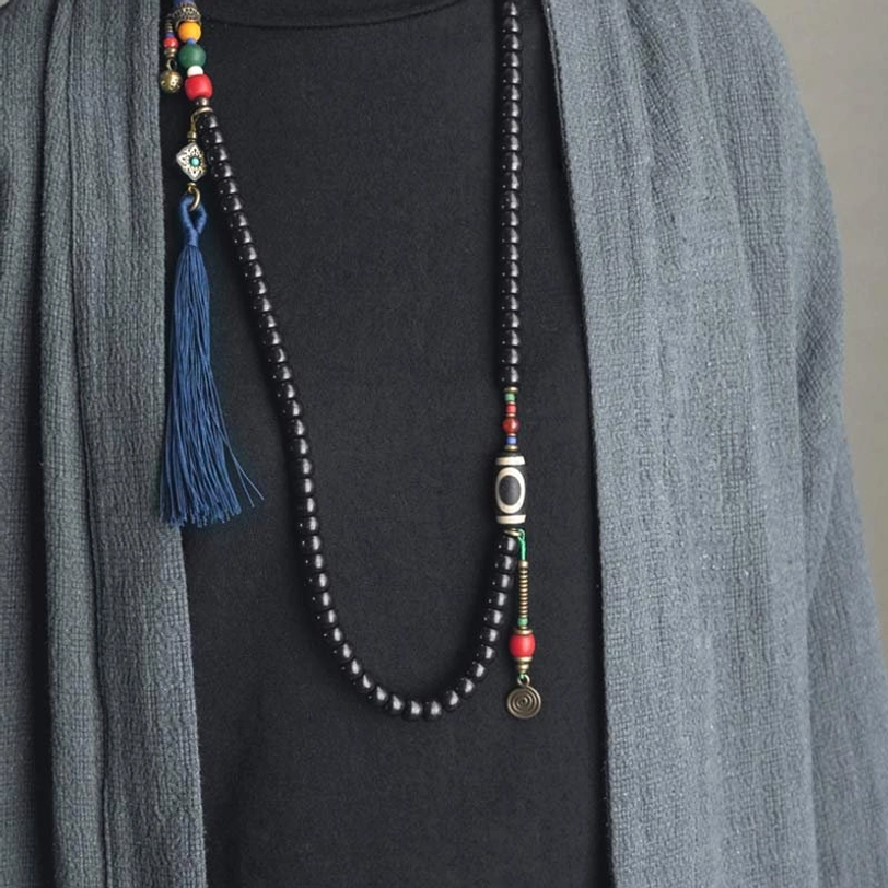 Long Tibetan 108-bead mala necklace draped over clothing showing full length with blue tassel and metal charms