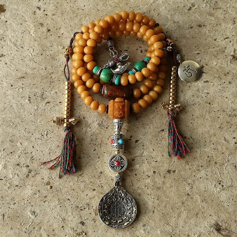 Tibetan 108 bodhi seed mala bracelet with copper Bagua vajra pendant and turquoise accents, flat lay top view on concrete texture