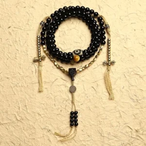 Tibetan 108 mala beads bracelet with black onyx and three-eyed dzi bead displayed in flat lay on textured background