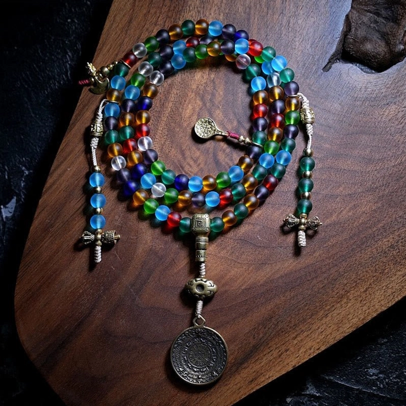 Complete Tibetan 108 mala bead set with rainbow frosted glass beads and multiple metal pendants including disc charm, overhead wooden board