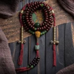 Tibetan 108 mala bracelet with purple bodhi seeds, hetian jade beads, and copper dorje charm in flat lay arrangement